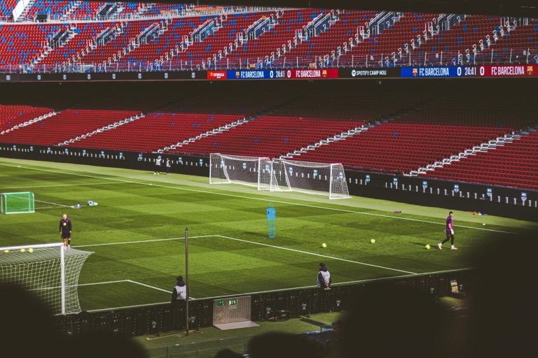 Soccer practice at a famous stadium with vibrant red seating and green field.